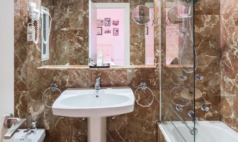 Salle de bain d'hôtel avant rénovation, marbre brun sombre